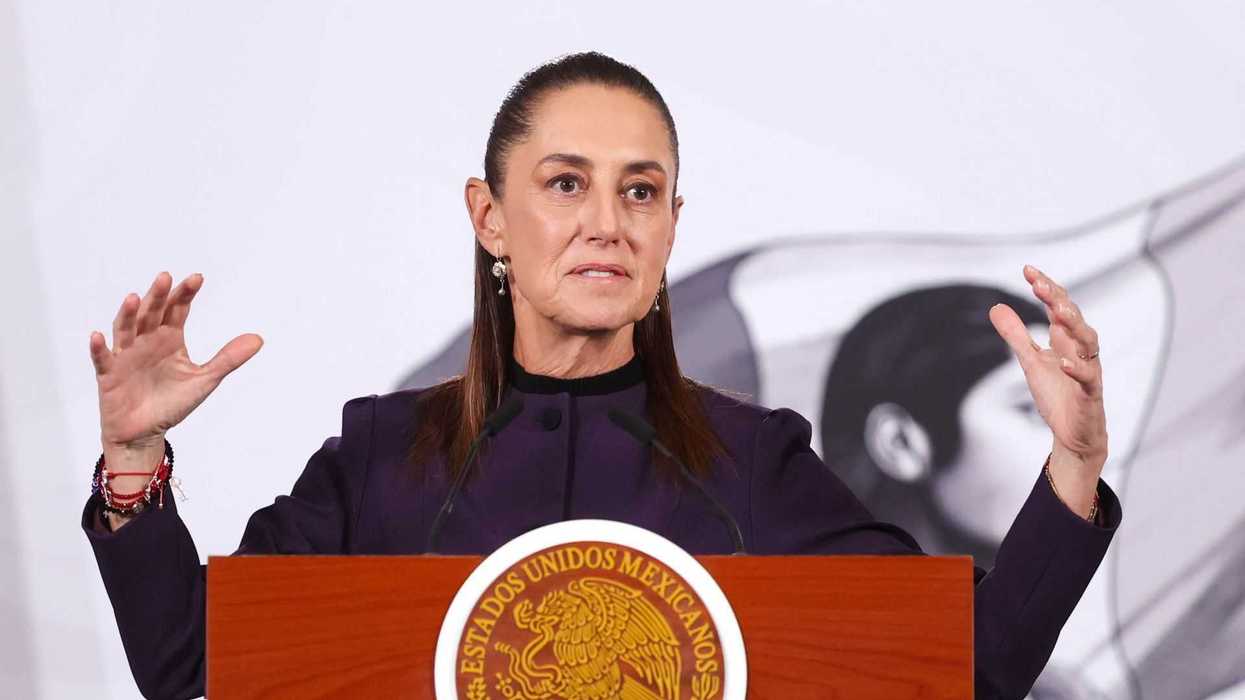 Woman speaking at a podium with the Mexican emblem, gesturing with both hands.