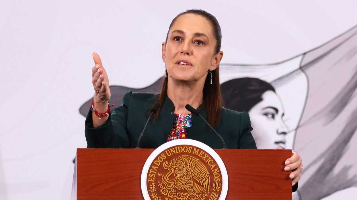 Woman speaking at a podium with the Mexican seal, background portrait visible.