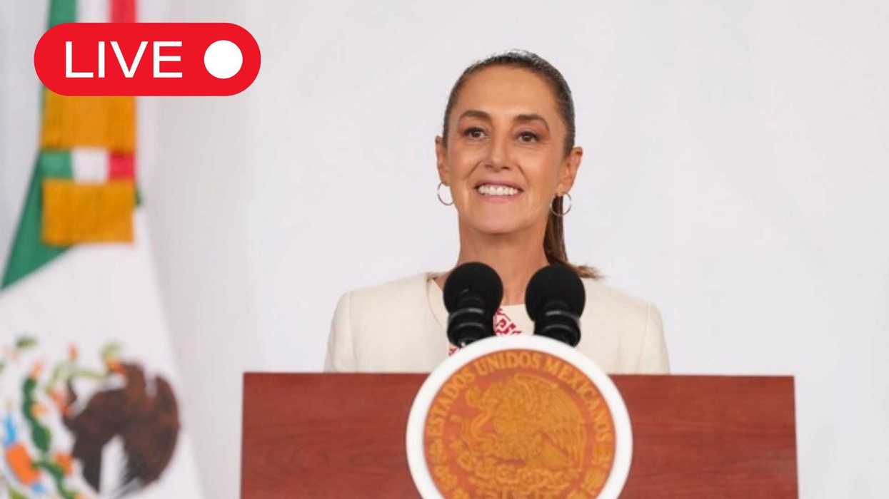 Woman speaking live at a podium with Mexican flag emblem.