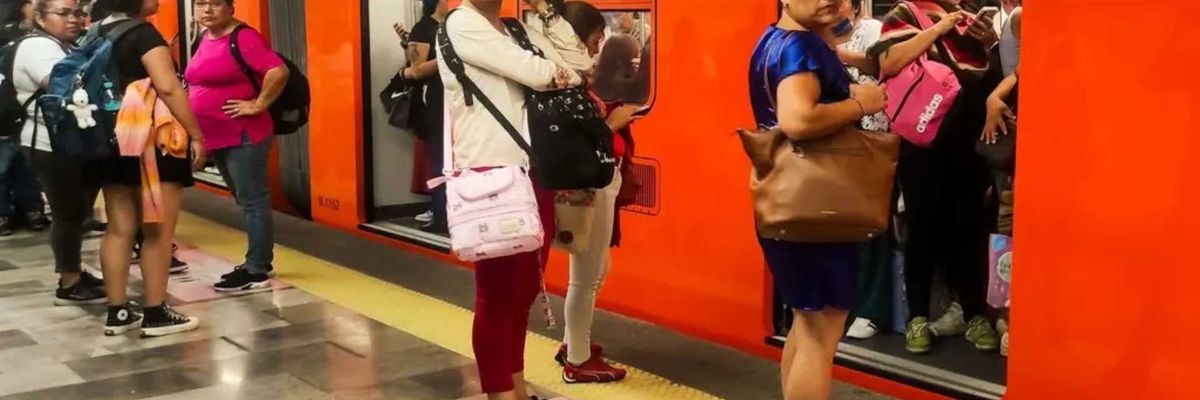 Women waiting at a crowded metro station with an orange train and open doors.