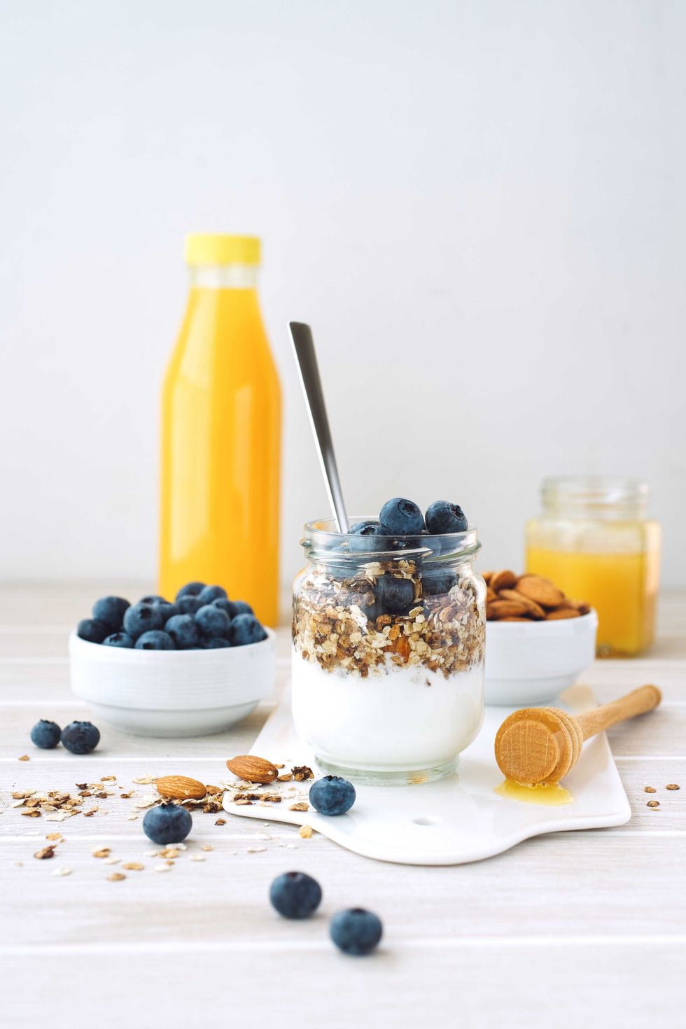 Yogurt parfait with blueberries and granola, orange juice in background.